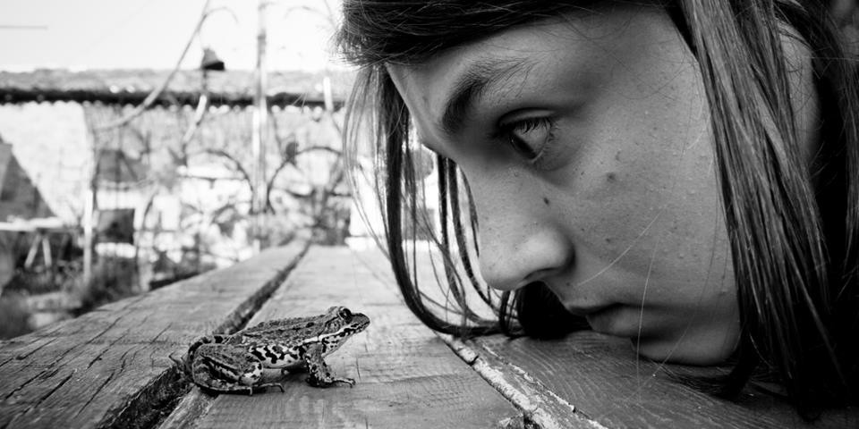 Alain Labels black and white photo of young girl staring at frog