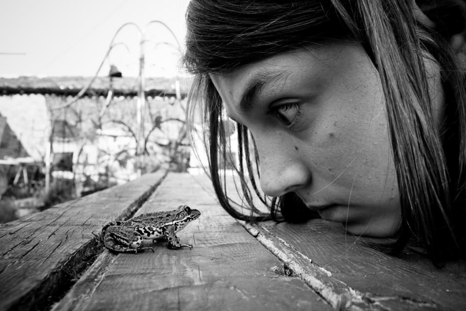 Alain Labels black and white photo of young girl staring at frog