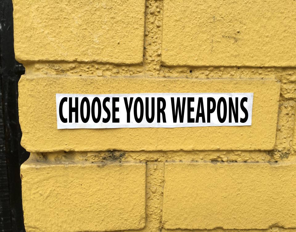 yellow brick wall with text choose your weapons for blog post at sandyhibbardcreative.com