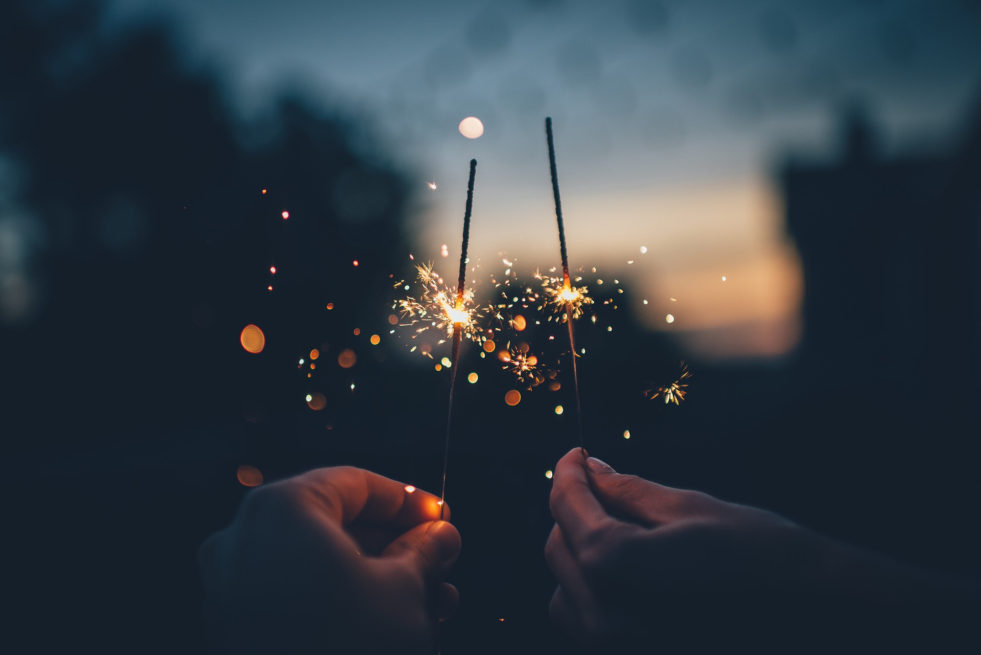 2 hands holding sparklers in dark